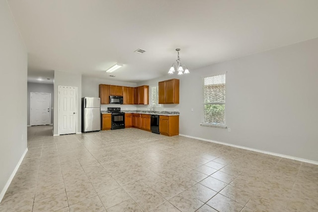 9008 Tall Sky Trce, Austin, TX 78724 - kitchen with black appliances, a chandelier, baseboards, brown cabinetry, and light tile patterned floors