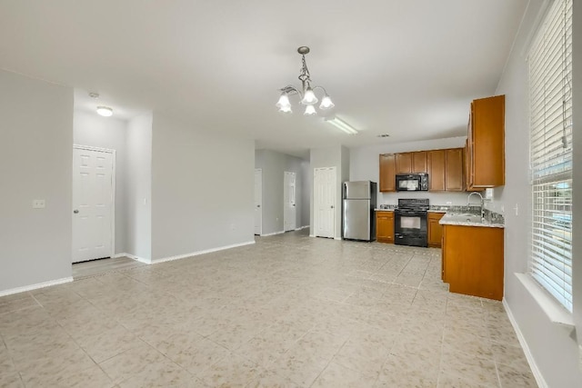 9008 Tall Sky Trce, Austin, TX 78724 - kitchen with black appliances, brown cabinetry, a chandelier, decorative light fixtures, and baseboards