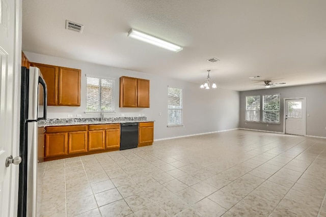 9008 Tall Sky Trce, Austin, TX 78724 - kitchen with black dishwasher, a chandelier, freestanding refrigerator, brown cabinetry, and open floor plan