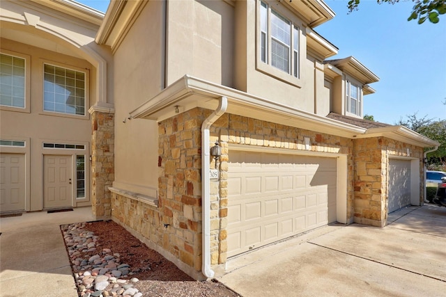 1101 E Parmer Ln Unit 305, Austin, TX 78753 - view of home's exterior featuring stone siding, a garage, and stucco siding