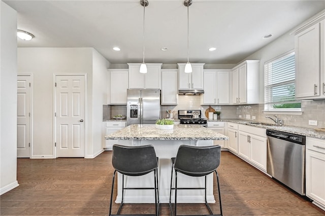 10612 Harwood Overlook Cv, Austin, TX 78747 - kitchen featuring stainless steel appliances, under cabinet range hood, a kitchen breakfast bar, a center island, and white cabinetry