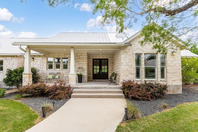 137 Lone Cypress Cv, Driftwood, TX 78619 - view of exterior entry featuring stone siding, french doors, a porch, a metal roof, and a standing seam roof