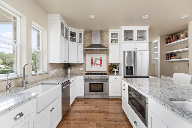137 Lone Cypress Cv, Driftwood, TX 78619 - kitchen featuring stainless steel appliances, wall chimney exhaust hood, a sink, backsplash, and white cabinets