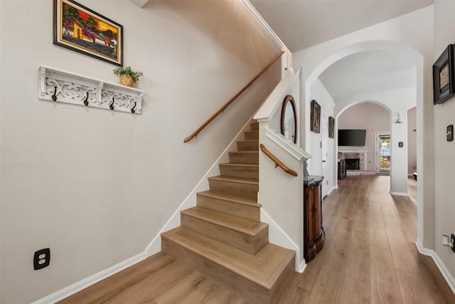 11113 Harvest Time Dr, Austin, TX 78754 - stairway with arched walkways, wood finished floors, and a fireplace with raised hearth