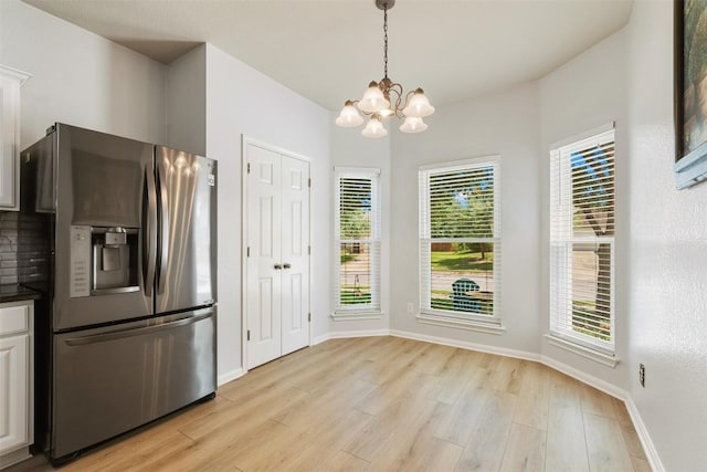 11113 Harvest Time Dr, Austin, TX 78754 - kitchen featuring stainless steel fridge, dark countertops, a chandelier, light wood finished floors, and baseboards