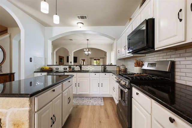 11113 Harvest Time Dr, Austin, TX 78754 - kitchen with gas range, black microwave, light wood-style floors, arched walkways, and tasteful backsplash
