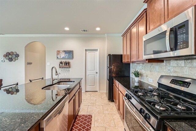 2712 Auburn Chestnut Ln, Pflugerville, TX 78660 - kitchen featuring appliances with stainless steel finishes, a sink, arched walkways, ornamental molding, and brown cabinets