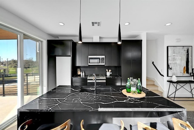 1117 Lawson Ln Unit 2, Austin, TX 78702 - kitchen featuring dark cabinetry, stainless steel microwave, tasteful backsplash, a sink, and recessed lighting