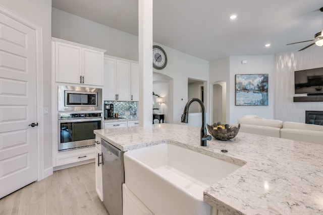 603 Arundel Rd, Austin, TX 78738 - kitchen with appliances with stainless steel finishes, a sink, open floor plan, a ceiling fan, and arched walkways