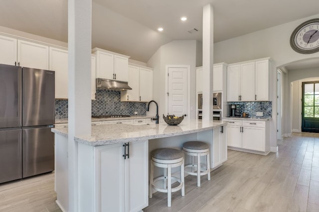 603 Arundel Rd, Austin, TX 78738 - kitchen featuring appliances with stainless steel finishes, under cabinet range hood, arched walkways, white cabinetry, and lofted ceiling