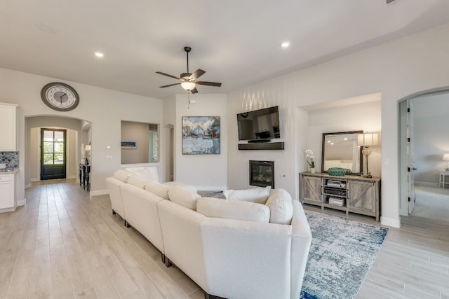 603 Arundel Rd, Austin, TX 78738 - living room with arched walkways, a large fireplace, ceiling fan, light wood finished floors, and recessed lighting