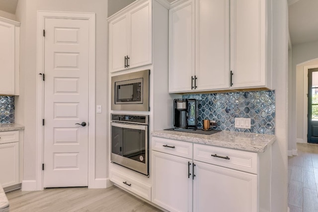 603 Arundel Rd, Austin, TX 78738 - kitchen with stainless steel appliances, light wood finished floors, backsplash, white cabinetry, and light stone countertops