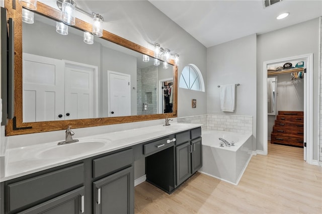 208 Sailors Run, Lakeway, TX 78734 - bathroom featuring a walk in closet, double vanity, a garden tub, wood finished floors, and a shower stall