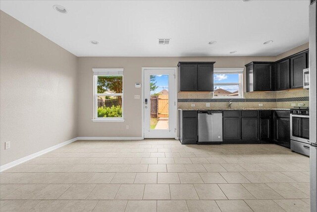 163 Wainscot Oak Way, San Marcos, TX 78666 - kitchen with appliances with stainless steel finishes, plenty of natural light, tasteful backsplash, dark cabinetry, and recessed lighting