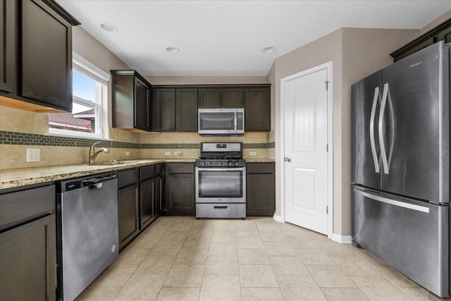 163 Wainscot Oak Way, San Marcos, TX 78666 - kitchen with appliances with stainless steel finishes, a sink, tasteful backsplash, light stone countertops, and dark brown cabinetry