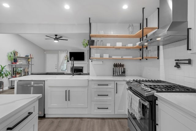 609 Blackberry Dr, Austin, TX 78745 - kitchen with gas range, wall chimney exhaust hood, stainless steel dishwasher, a sink, and a ceiling fan