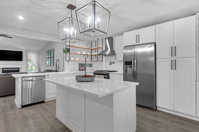 609 Blackberry Dr, Austin, TX 78745 - kitchen with appliances with stainless steel finishes, wall chimney exhaust hood, a sink, open floor plan, and light wood finished floors