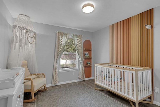 609 Blackberry Dr, Austin, TX 78745 - bedroom featuring wood finished floors, a nursery area, and baseboards