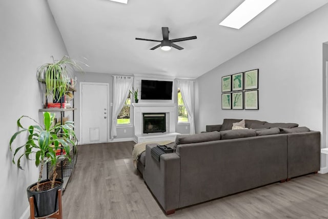 609 Blackberry Dr, Austin, TX 78745 - living room featuring vaulted ceiling, ceiling fan, light wood-style flooring, a fireplace, and a skylight