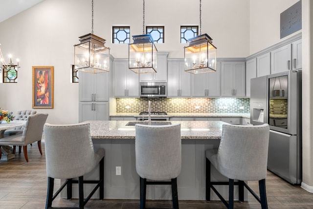 121 Cartwheel Bnd Unit 42, Austin, TX 78738 - kitchen featuring appliances with stainless steel finishes, a chandelier, a high ceiling, and light stone counters