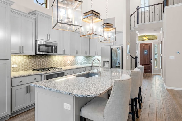 121 Cartwheel Bnd Unit 42, Austin, TX 78738 - kitchen with stainless steel appliances, a sink, a high ceiling, wood finished floors, and a chandelier