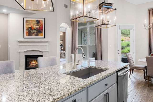 121 Cartwheel Bnd Unit 42, Austin, TX 78738 - kitchen featuring a chandelier, a glass covered fireplace, light stone counters, hanging light fixtures, and dishwasher