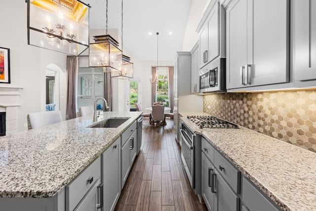 121 Cartwheel Bnd Unit 42, Austin, TX 78738 - kitchen with gray cabinets, stainless steel appliances, arched walkways, dark wood finished floors, and light stone counters