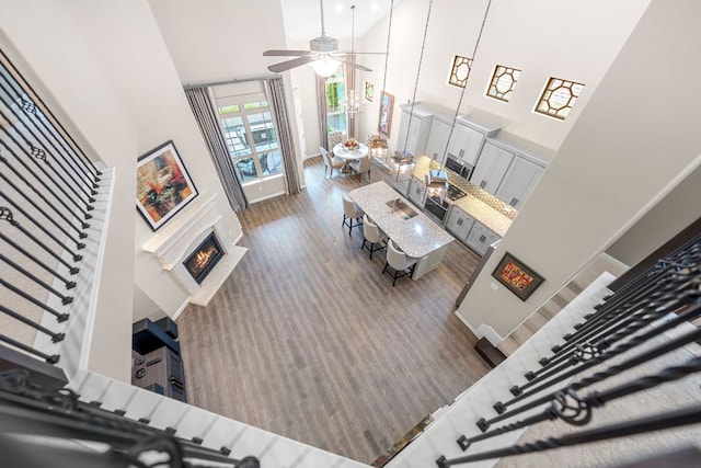 121 Cartwheel Bnd Unit 42, Austin, TX 78738 - living room with high vaulted ceiling, a ceiling fan, a lit fireplace, wood finished floors, and stairway