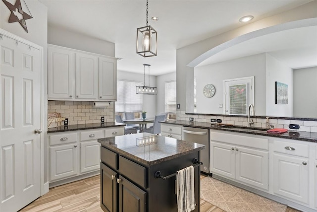 2021 Kimbrook Dr, Round Rock, TX 78681 - kitchen featuring stainless steel dishwasher, arched walkways, a sink, backsplash, and white cabinetry