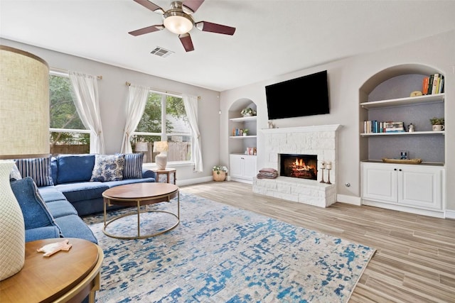 2021 Kimbrook Dr, Round Rock, TX 78681 - living area with a ceiling fan, wood finished floors, built in shelves, baseboards, and a stone fireplace