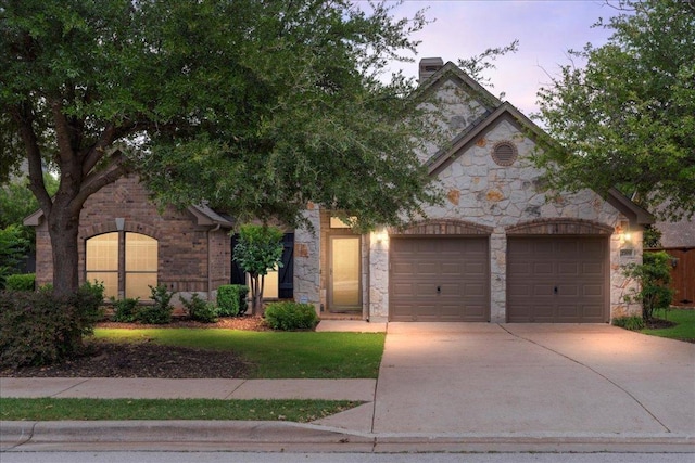 2709 Sun Mountain Dr, Leander, TX 78641 - view of front of house with stone siding, an attached garage, concrete driveway, and a chimney