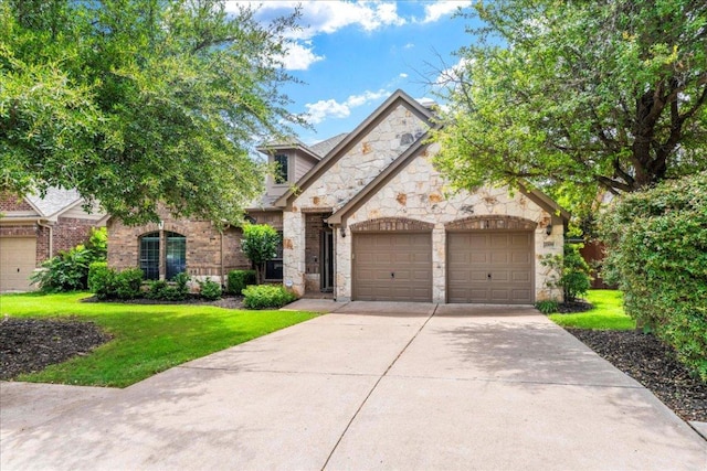 2709 Sun Mountain Dr, Leander, TX 78641 - french country inspired facade featuring stone siding, an attached garage, driveway, and a front lawn