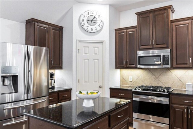 2709 Sun Mountain Dr, Leander, TX 78641 - kitchen featuring stainless steel appliances, tasteful backsplash, dark stone counters, and dark brown cabinetry