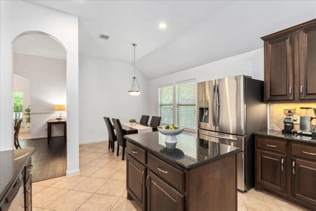 2709 Sun Mountain Dr, Leander, TX 78641 - kitchen featuring stainless steel refrigerator with ice dispenser, vaulted ceiling, dark brown cabinets, dark stone countertops, and a center island