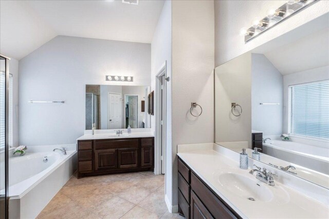 2709 Sun Mountain Dr, Leander, TX 78641 - bathroom with vaulted ceiling, two vanities, a bath, a stall shower, and healthy amount of natural light