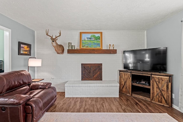 237 Oak Park Two, Rockdale, TX 76567 - living room with wood finished floors, a textured ceiling, and brick wall