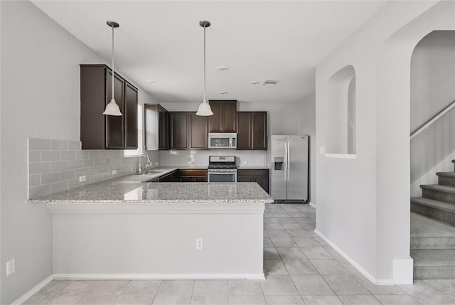 144 Holstein St, Hutto, TX 78634 - kitchen featuring stainless steel appliances, dark brown cabinetry, decorative backsplash, light stone counters, and a peninsula