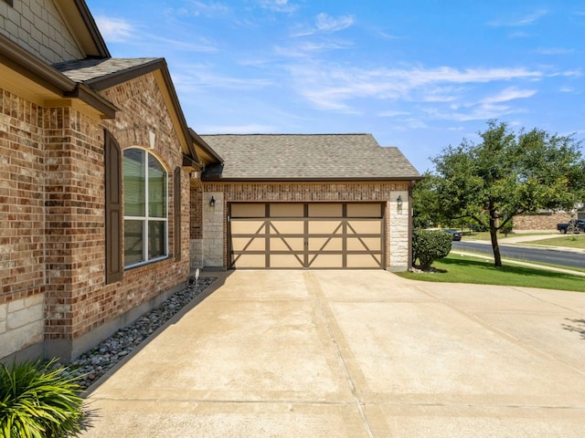 18401 Pencil Cactus Dr, Pflugerville, TX 78660 - view of side of home with brick siding, roof with shingles, concrete driveway, and an attached garage