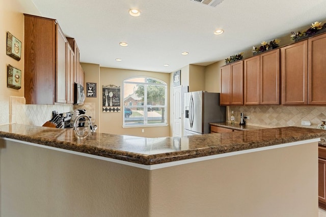 18401 Pencil Cactus Dr, Pflugerville, TX 78660 - kitchen with stainless steel appliances, a peninsula, dark stone countertops, backsplash, and recessed lighting