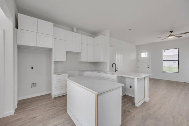 138 Blushing Dr, Cedar Creek, TX 78612 - kitchen with a sink, a center island, ceiling fan, a peninsula, and light wood-style floors