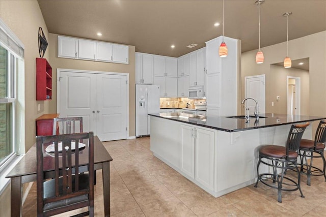 721 Deer Run, Wimberley, TX 78676 - kitchen with white appliances, white cabinetry, a breakfast bar area, light tile patterned flooring, and plenty of natural light