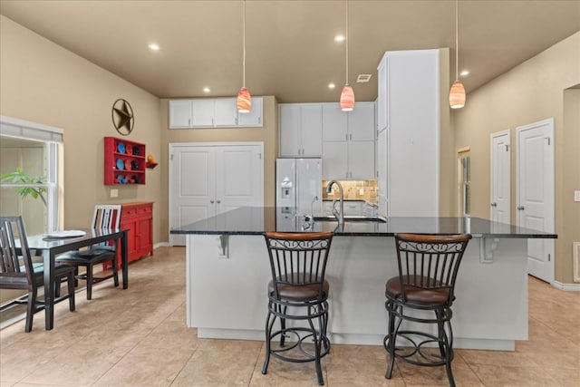 721 Deer Run, Wimberley, TX 78676 - kitchen featuring a kitchen bar, white refrigerator with ice dispenser, recessed lighting, white cabinets, and light tile patterned floors