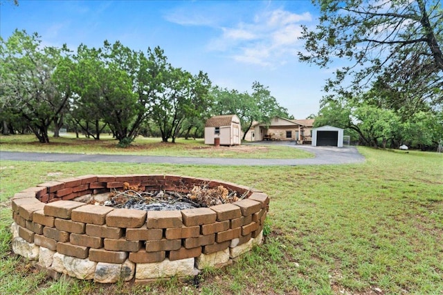 721 Deer Run, Wimberley, TX 78676 - view of green lawn featuring a fire pit, a storage shed, a garage, and driveway