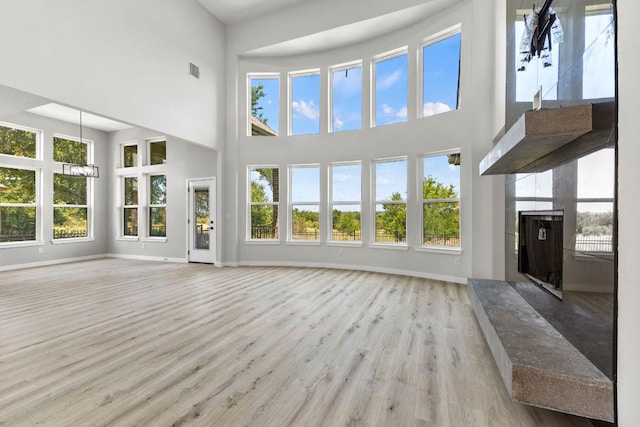 210 Las Colinas Dr, Georgetown, TX 78628 - unfurnished living room featuring a towering ceiling, wood finished floors, baseboards, plenty of natural light, and a high end fireplace
