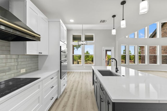 210 Las Colinas Dr, Georgetown, TX 78628 - kitchen featuring wall chimney range hood, a sink, recessed lighting, light wood finished floors, and a center island with sink