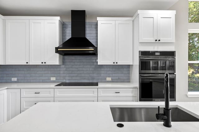 210 Las Colinas Dr, Georgetown, TX 78628 - kitchen with wall chimney range hood, stainless steel double oven, a sink, decorative backsplash, and white cabinetry