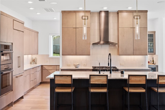 120 July Johnson Dr, Austin, TX 78737 - kitchen featuring wall chimney exhaust hood, modern cabinets, light brown cabinets, a breakfast bar area, and recessed lighting