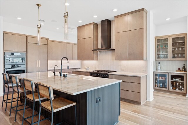 120 July Johnson Dr, Austin, TX 78737 - kitchen with wall chimney exhaust hood, a breakfast bar area, light stone counters, tasteful backsplash, and a spacious island