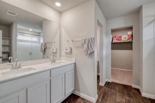 19413 Abigail Fillmore Rd, Manor, TX 78653 - full bathroom featuring a shower stall, double vanity, wood finished floors, a spacious closet, and baseboards