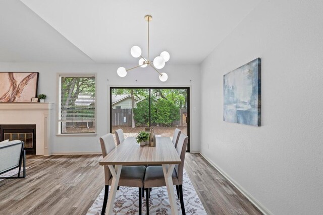 1706 Prairie Hen Cv, Austin, TX 78758 - dining room featuring wood finished floors, baseboards, a chandelier, and a glass covered fireplace